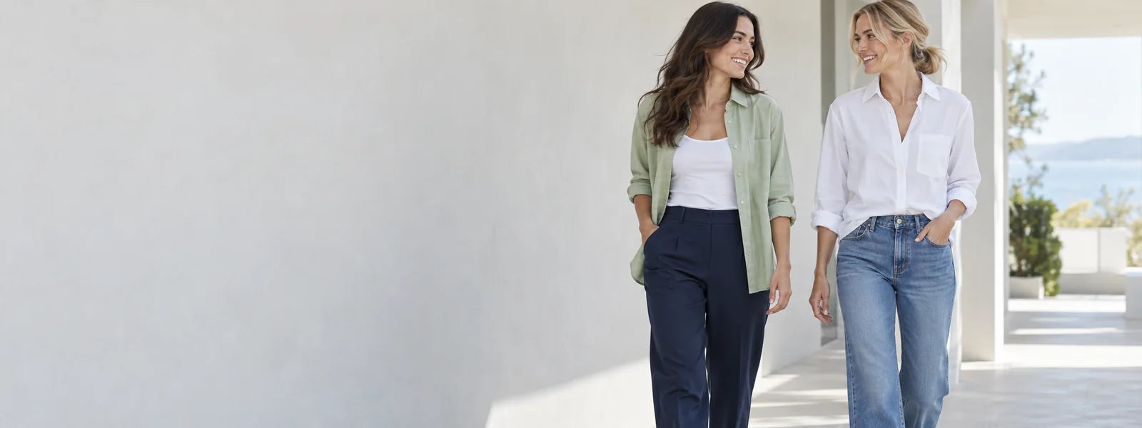 Two women wearing relaxed green, white and navy everyday outfits in a sunlit space.